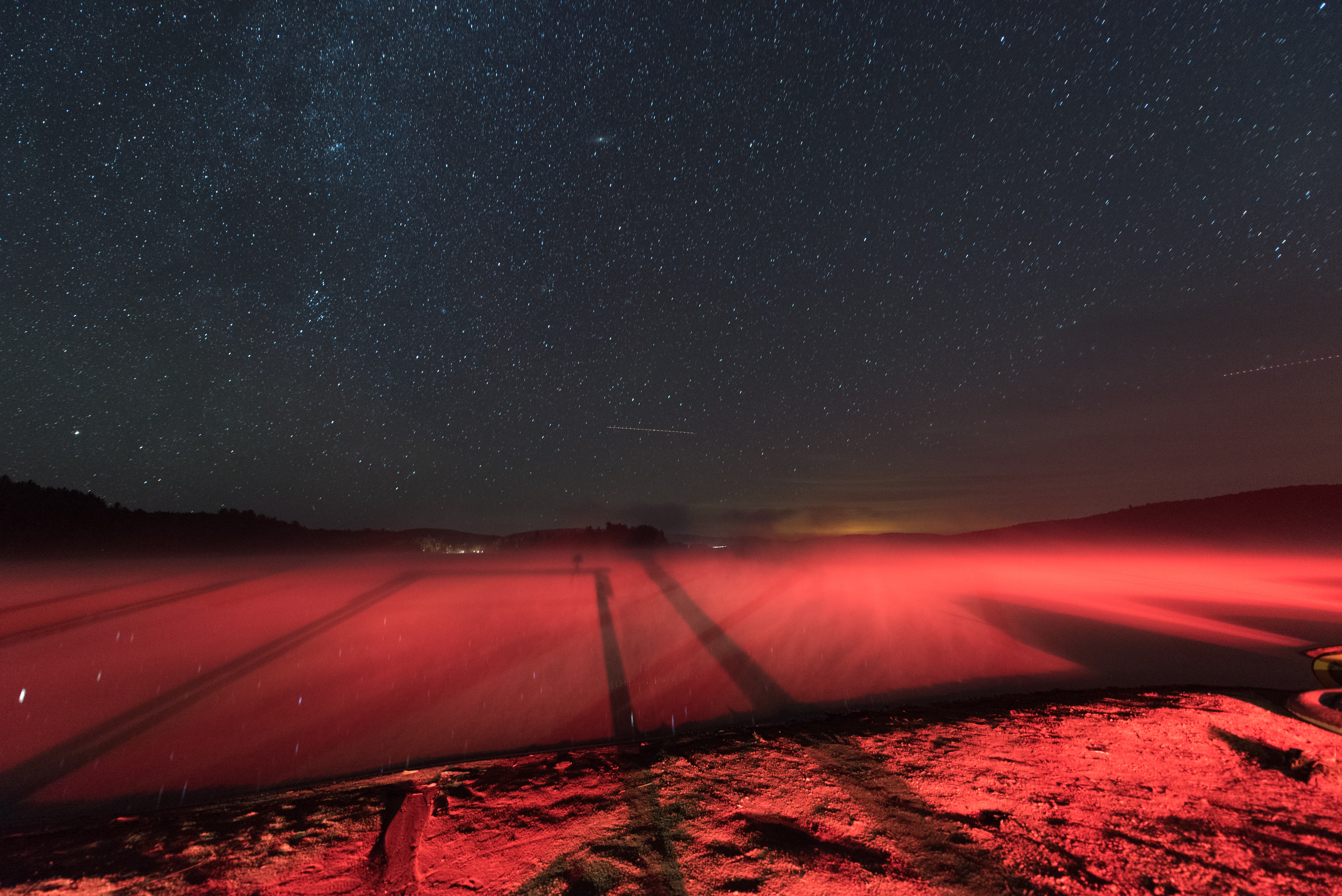 See mit rotem Licht überzogen. Obendran der Sternenhimmel